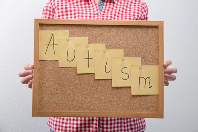 Photo of Woman holding board with word "Autism" on light background