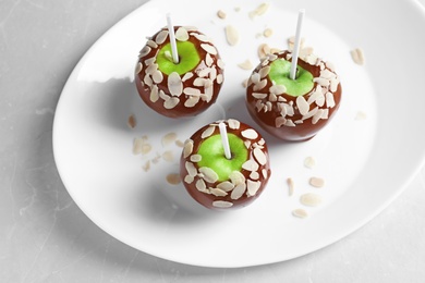 Plate with delicious caramel apples on light background