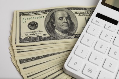 Money exchange. Dollar banknotes and calculator on white background, closeup