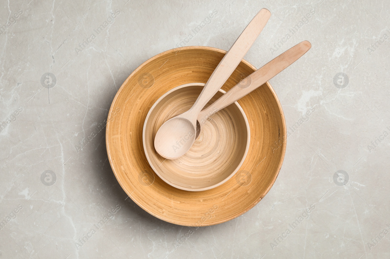 Photo of Wooden spoons in bowls on grey table, top view. Cooking utensils