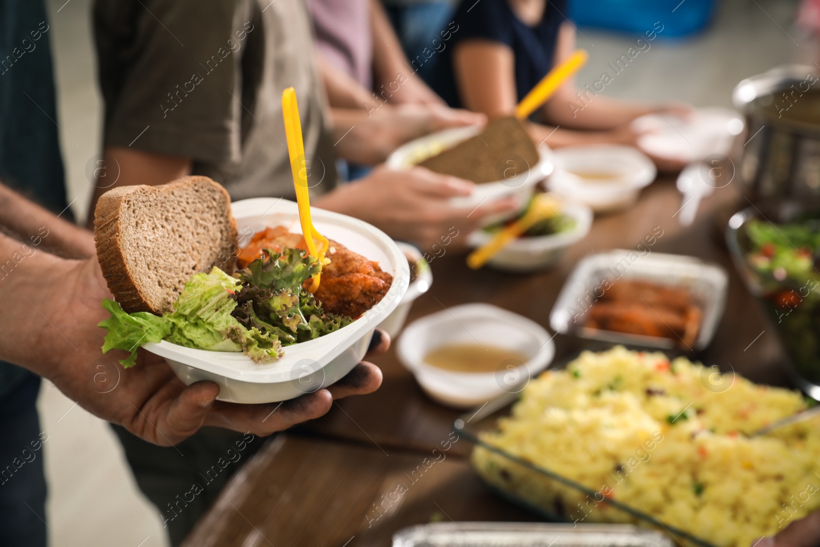Photo of Poor man holding plate with food in charity centre, closeup