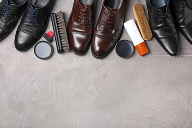Photo of Flat lay composition with footwear and shoe shine kit on grey surface, space for text