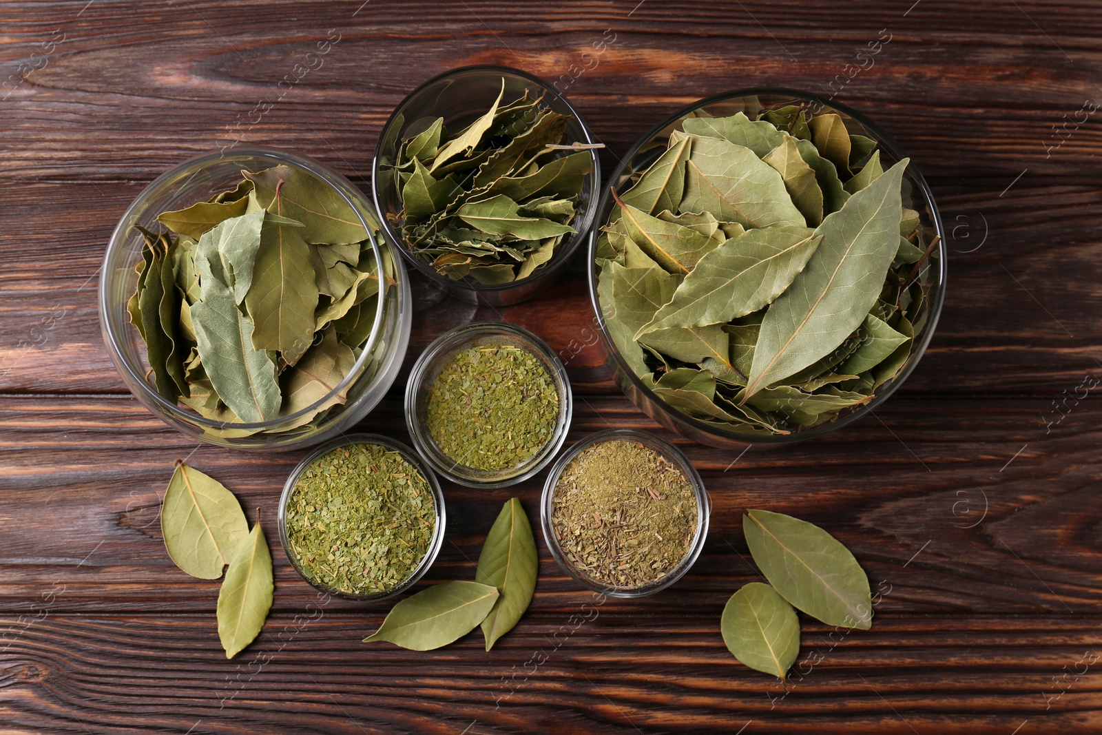 Photo of Whole and ground bay leaves on wooden table, flat lay