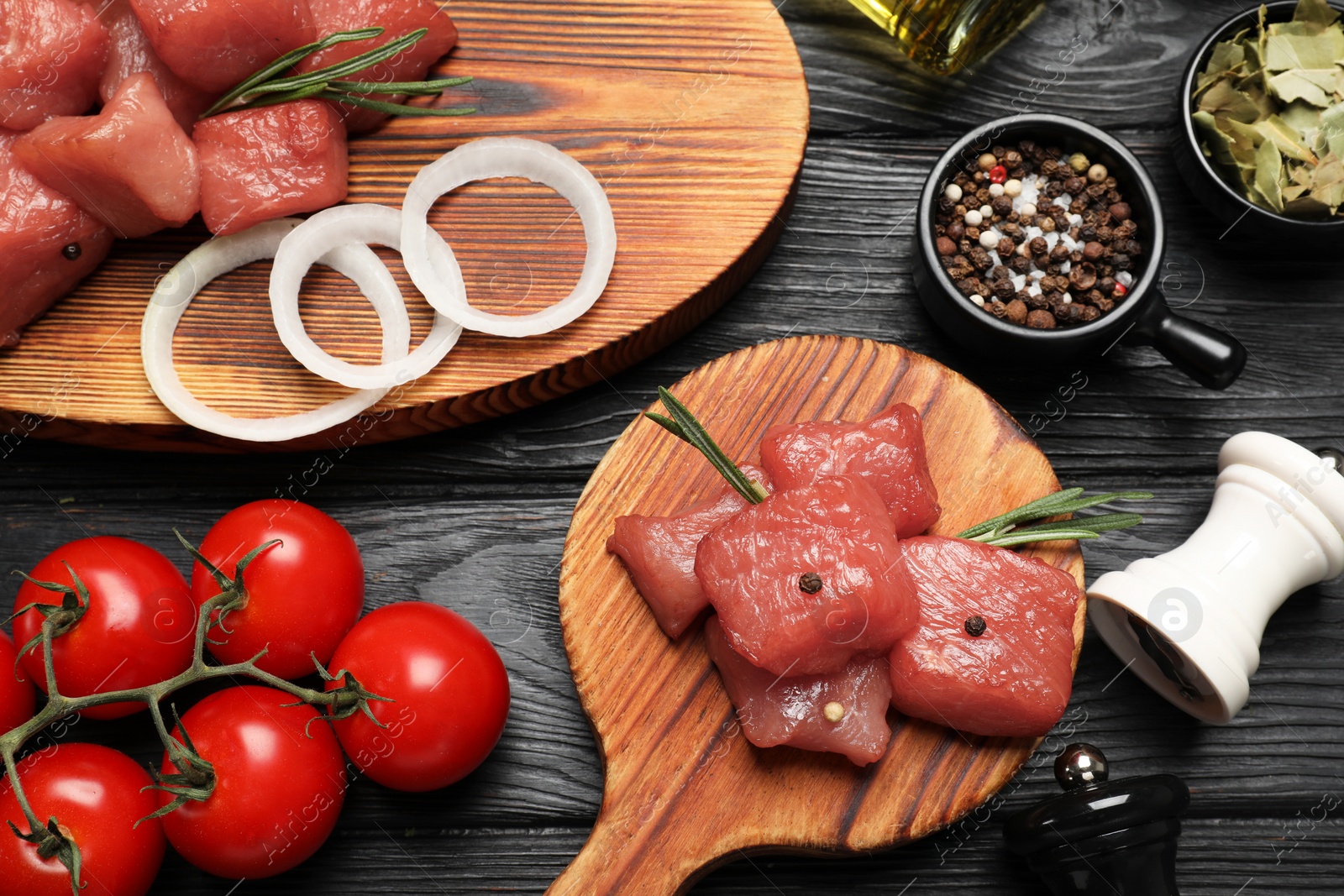 Photo of Raw beef meat and different ingredients for cooking delicious goulash on black wooden table, flat lay