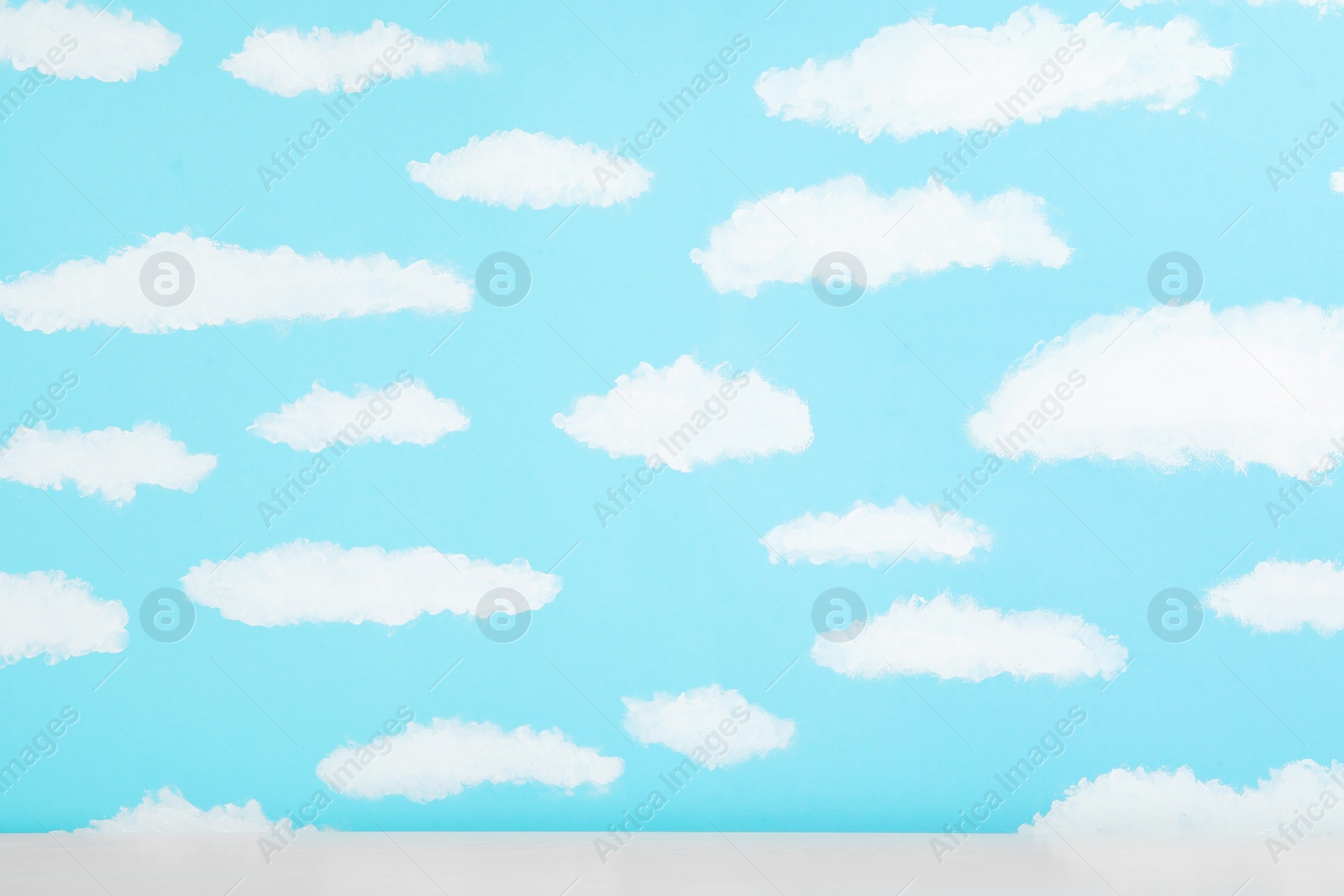 Photo of White table near wall with painted blue sky. Idea for baby room interior