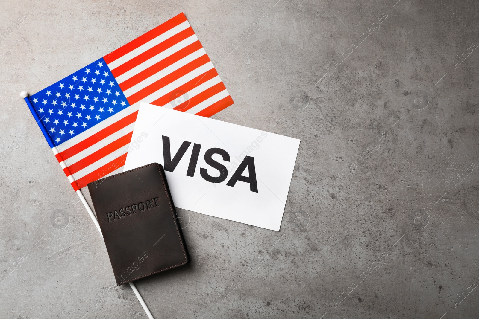 Photo of Flat lay composition with flag of USA, passport and word VISA on gray background. Space for text