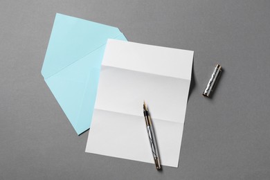 Photo of Blank sheet of paper, letter envelope and pen on grey background, top view