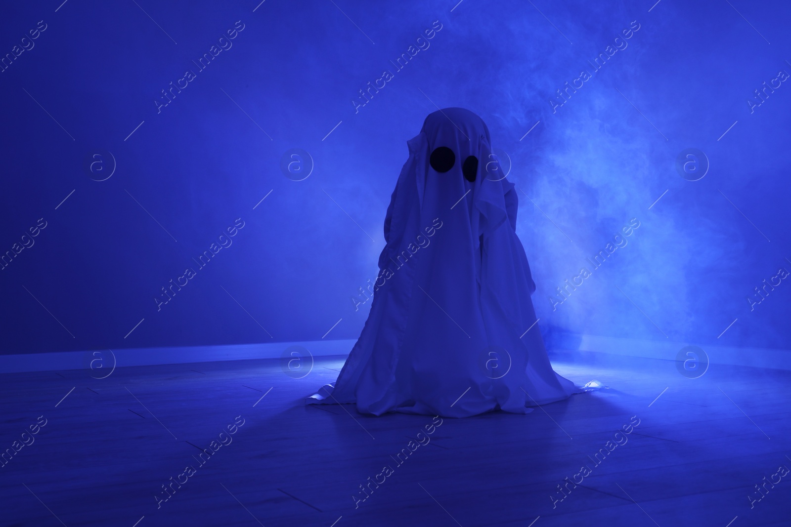 Photo of Creepy ghost. Woman covered with sheet in blue light