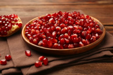 Photo of Ripe juicy pomegranates and grains on wooden table