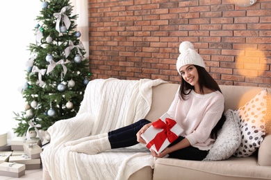 Photo of Beautiful young woman in hat with gift box at home. Christmas celebration