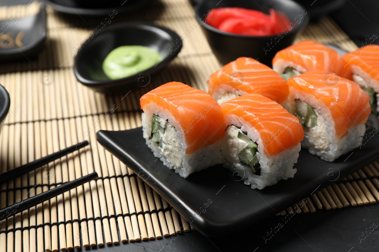 Photo of Tasty sushi rolls served on black table, closeup