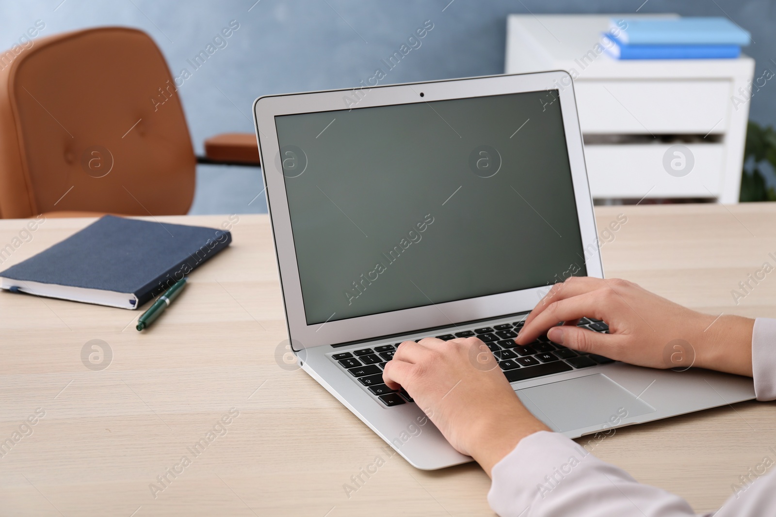 Photo of Woman using new modern laptop at wooden table in office, closeup