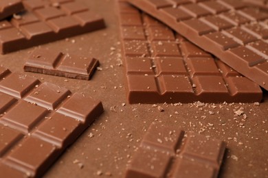 Pieces of tasty chocolate on brown background