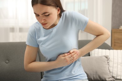 Woman having heart attack on sofa at home