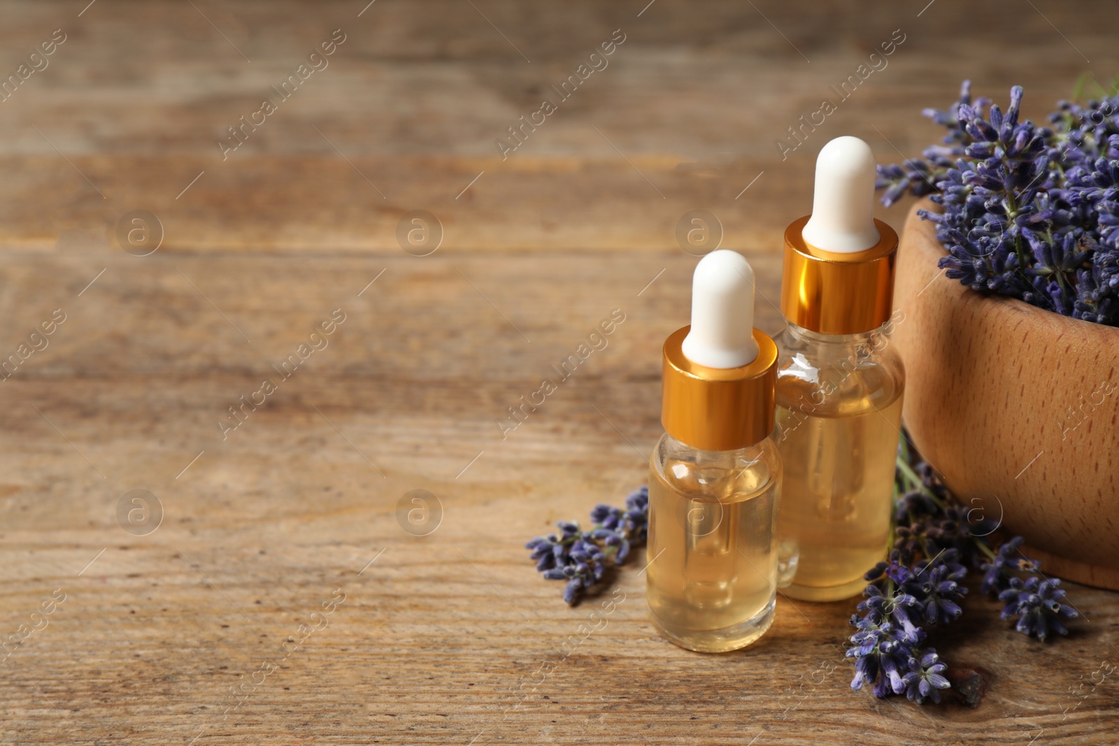 Photo of Beautiful lavender flowers and natural essential oil on wooden table. Space for text