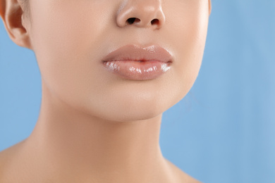 Young woman with beautiful full lips on light blue background, closeup