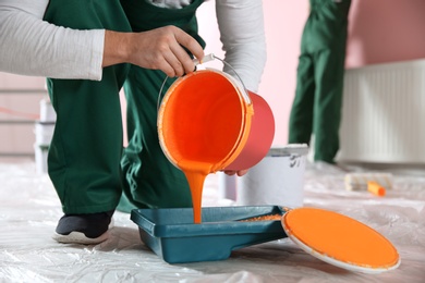 Photo of Professional decorator with bucket of paint indoors, closeup. Home repair service