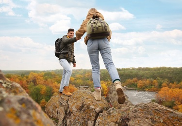 Couple of hikers with backpacks climbing up mountains