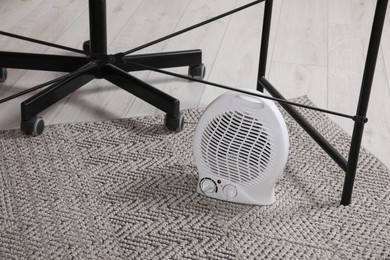 Photo of Modern electric fan heater on floor indoors