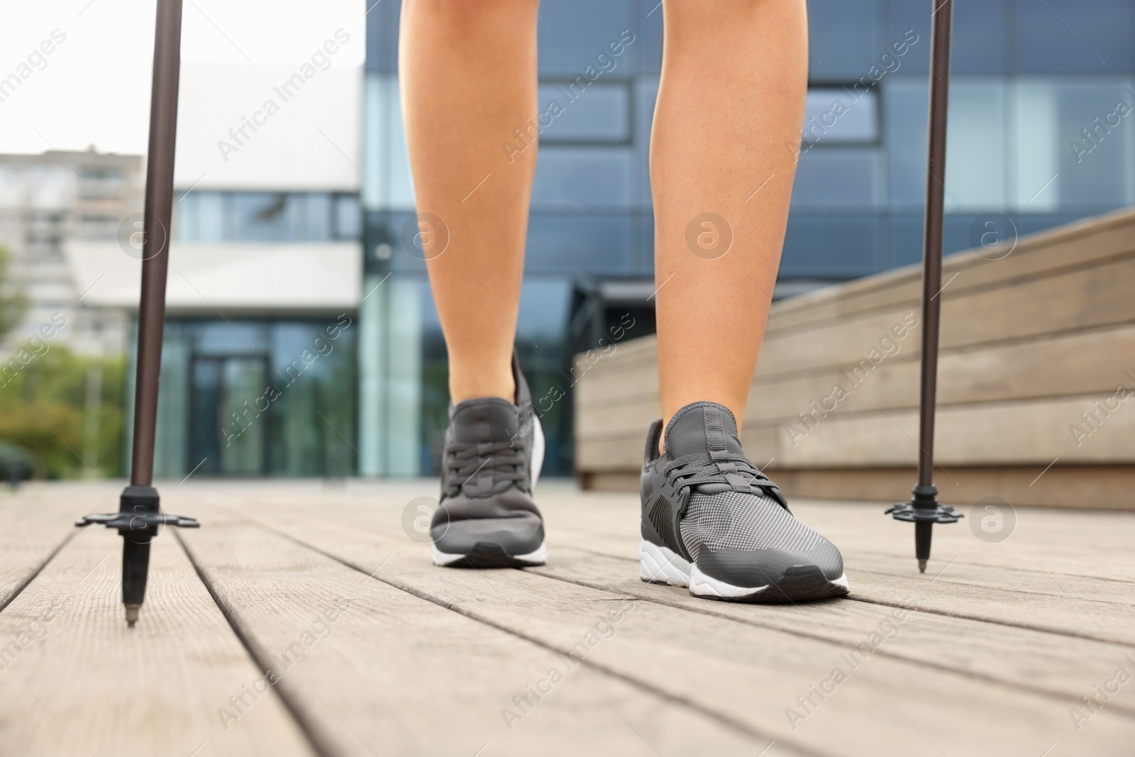 Photo of Young woman practicing Nordic walking with poles outdoors, closeup