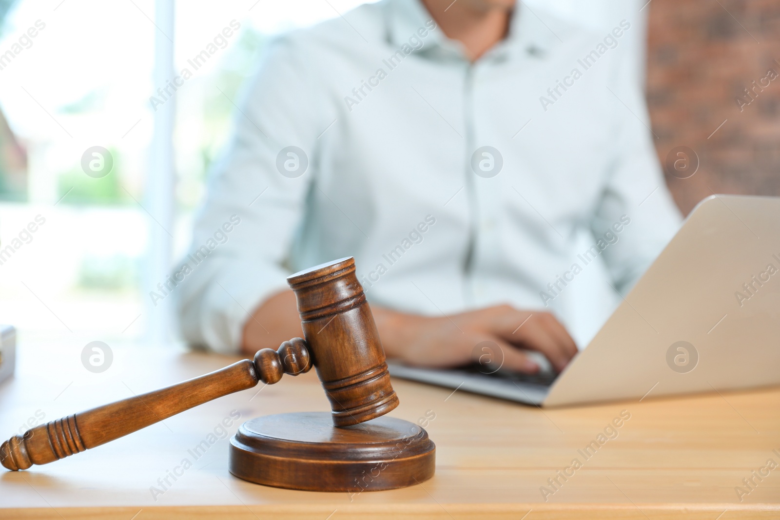 Photo of Wooden gavel and blurred notary with laptop on background