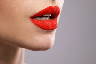 Young woman with beautiful red lips on grey background, closeup. Space for text