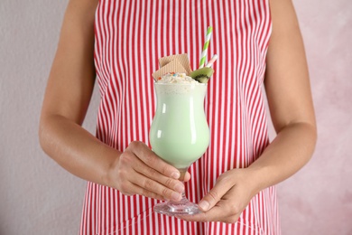 Photo of Woman with glass of delicious milk shake on color background, closeup