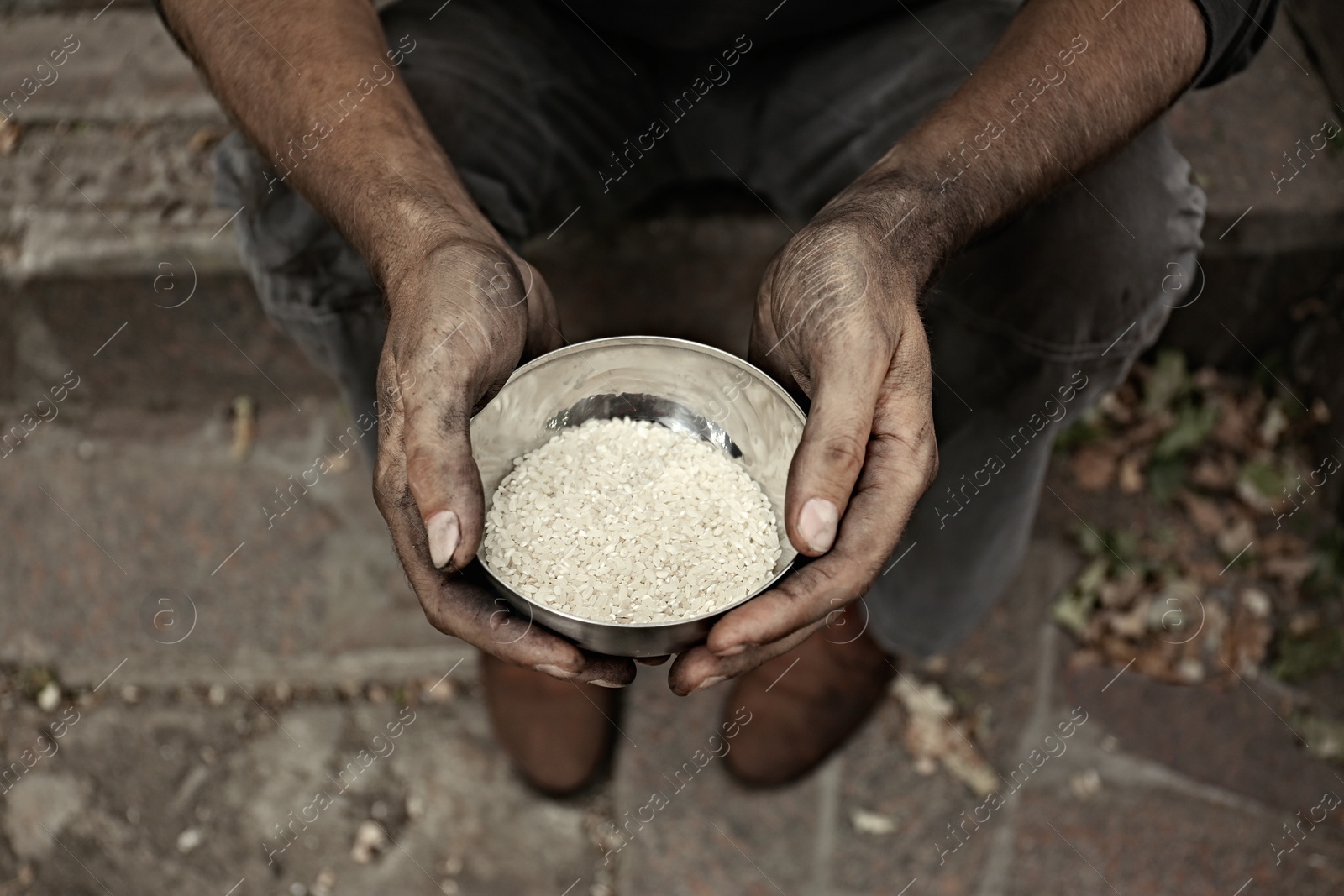 Photo of Poor homeless man with bowl of rice outdoors, closeup