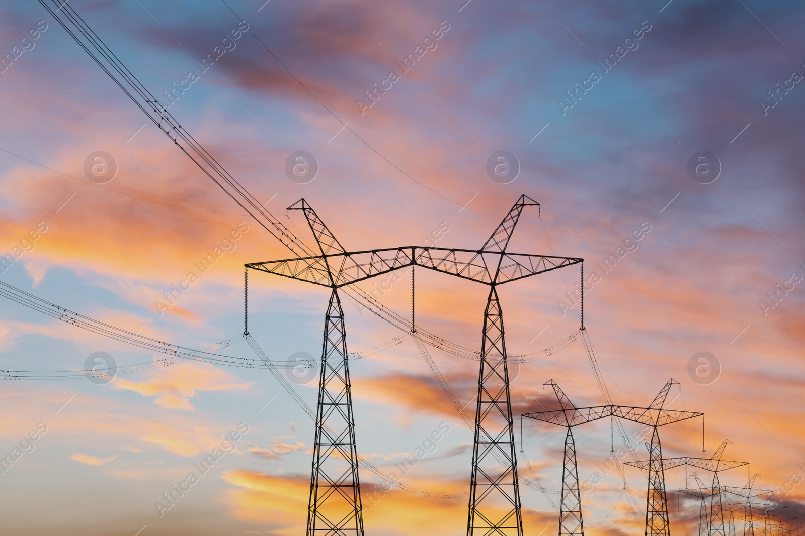 Photo of Telephone poles with cables at sunset outdoors