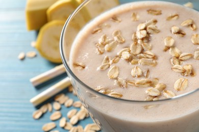 Glass of tasty banana smoothie with oatmeal on light blue table, closeup