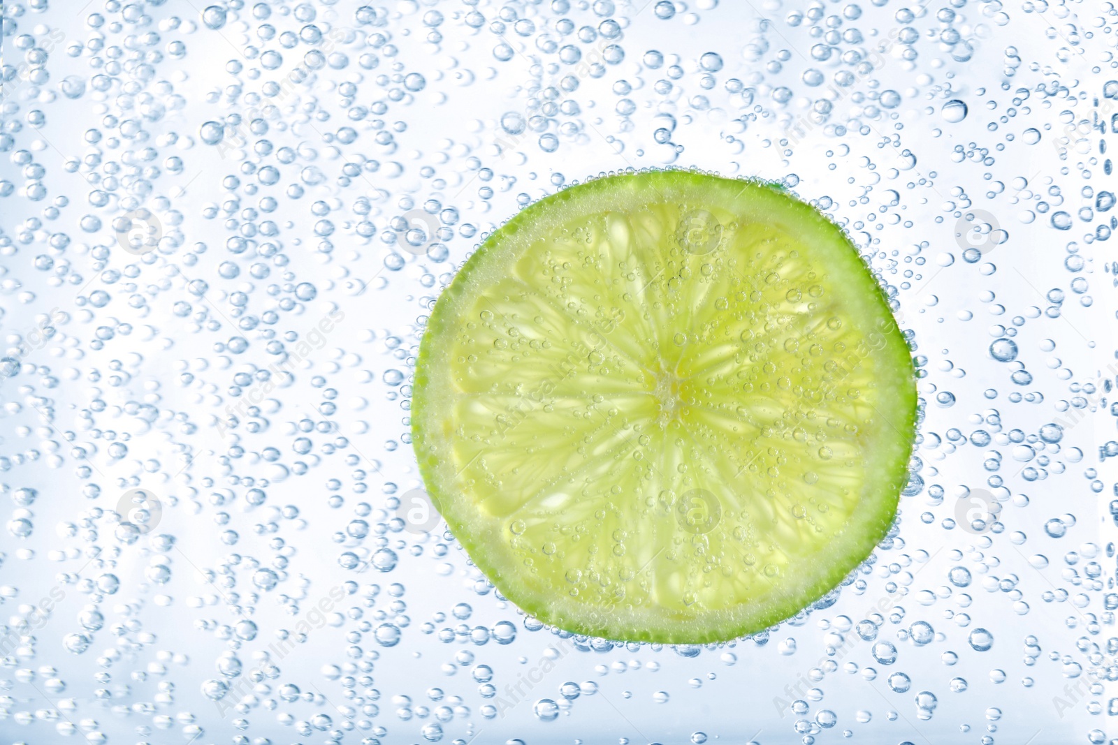 Photo of Juicy lime slice in soda water, closeup