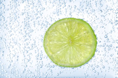 Photo of Juicy lime slice in soda water, closeup