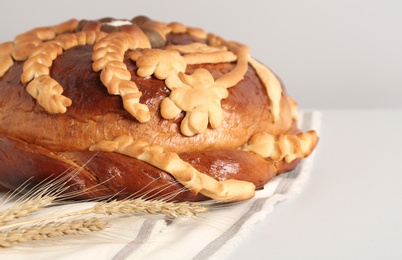 Photo of Korovai with wheat spikes on white table, closeup. Ukrainian bread and salt welcoming tradition