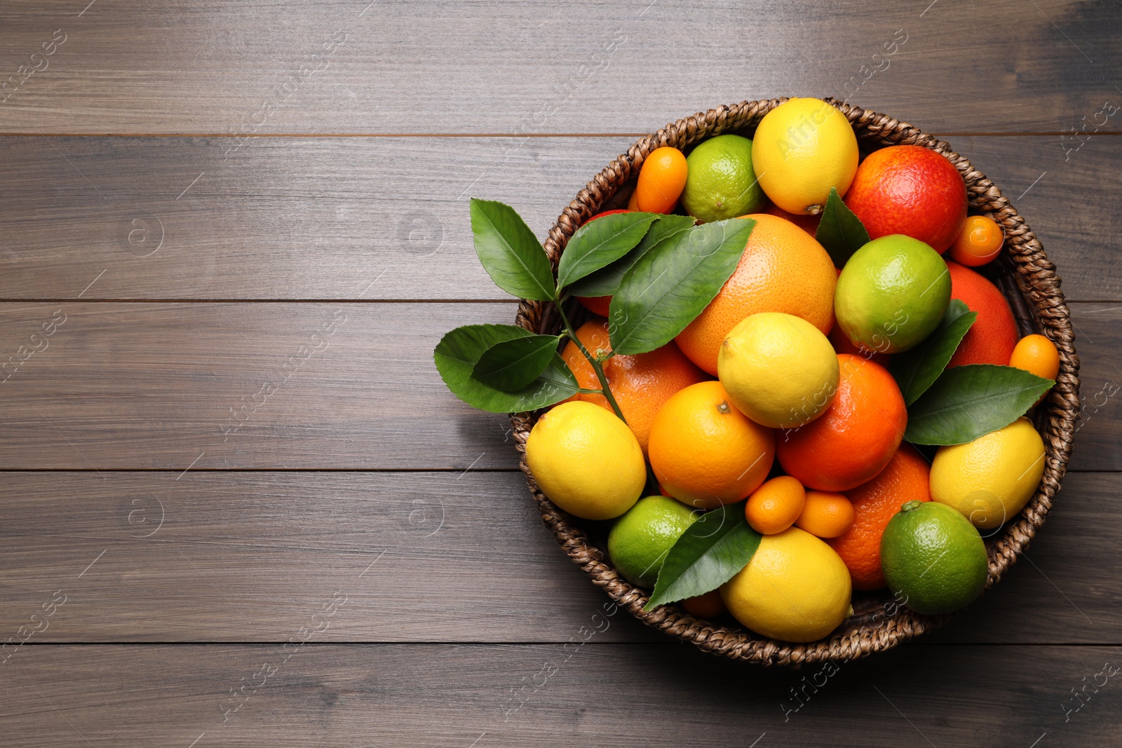 Photo of Different citrus fruits on wooden table, top view. Space for text