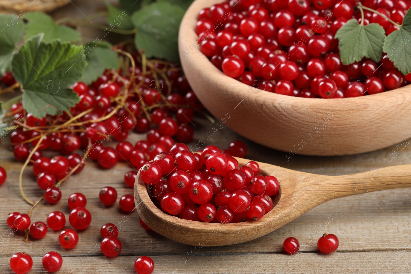 Photo of Ripe red currants and leaves on wooden table