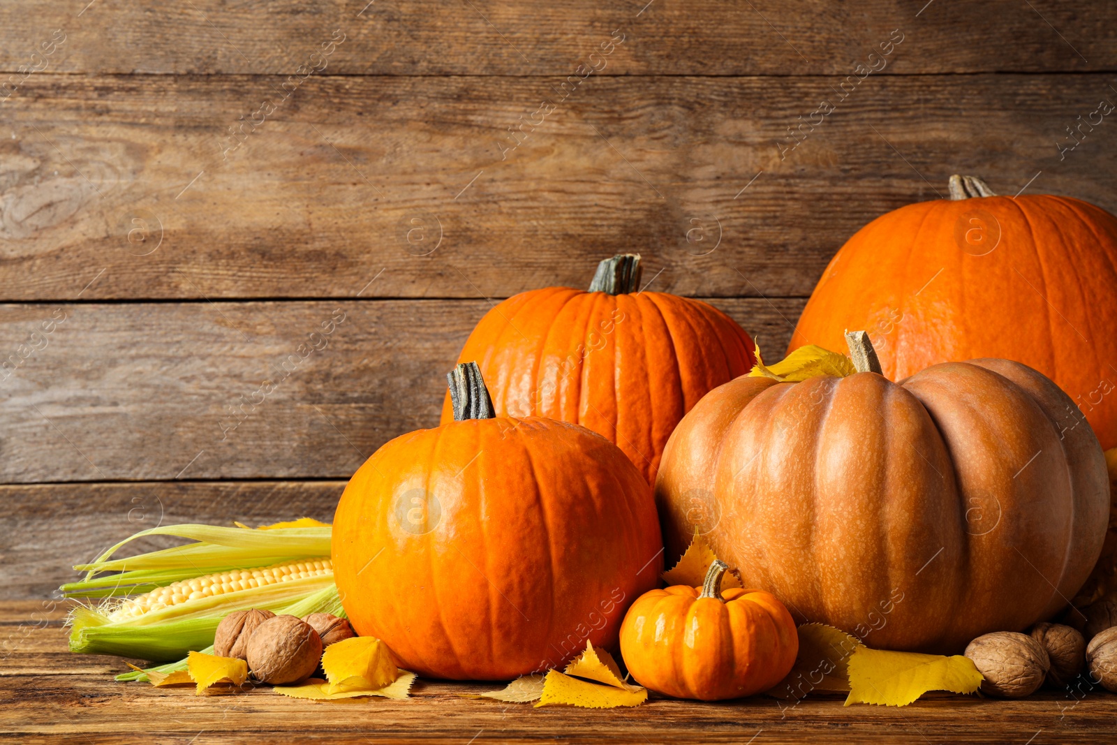 Photo of Composition with ripe pumpkins and autumn leaves on wooden table. Happy Thanksgiving day