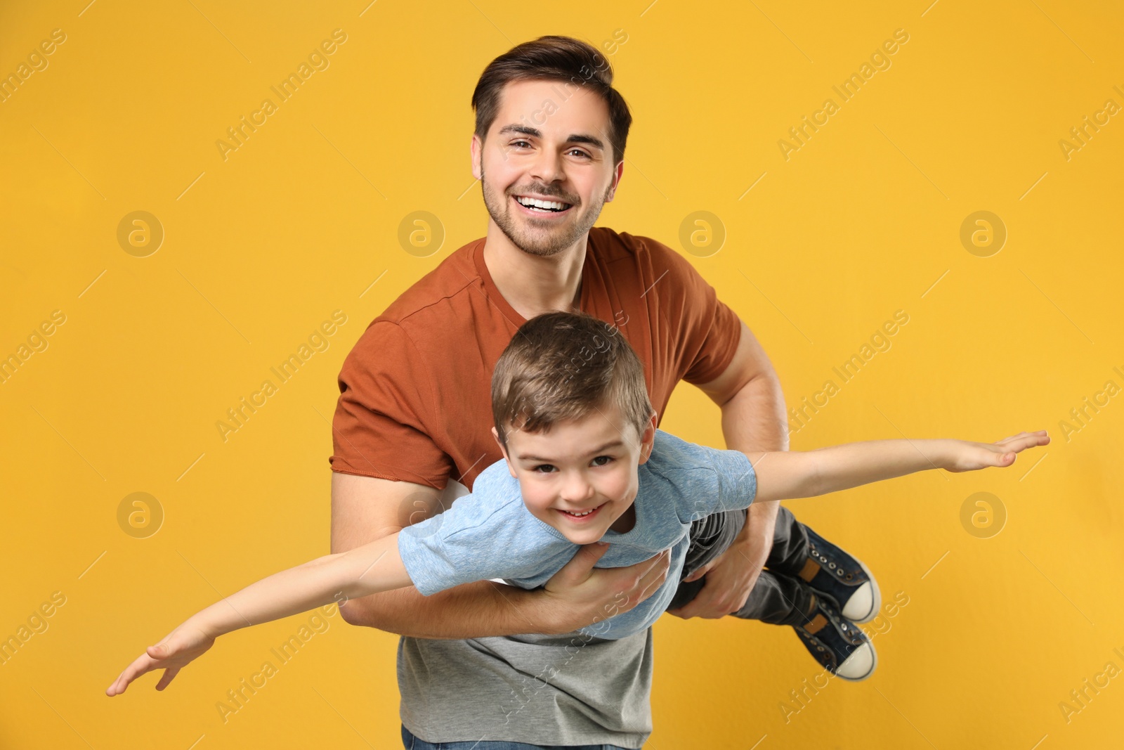 Photo of Portrait of dad playing with his son on color background