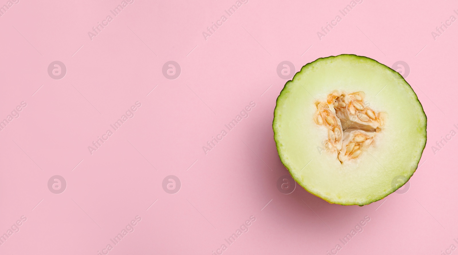 Photo of Half of ripe tasty melon on pink background, top view. Space for text