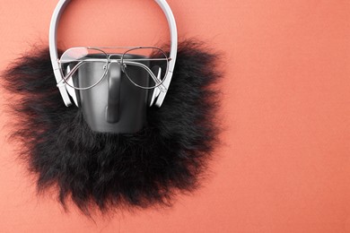 Man's face made of artificial beard, headphones and glasses on terracotta background, top view. Space for text