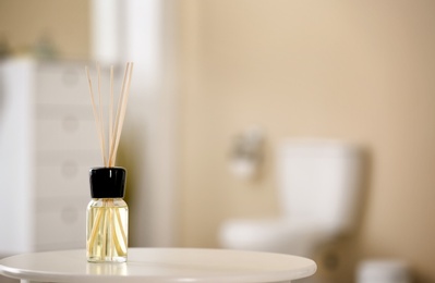 Photo of Aromatic reed air freshener on table against blurred background