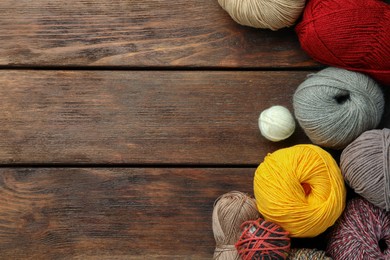 Photo of Soft woolen yarns on wooden table, flat lay. Space for text