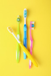 Photo of Different toothbrushes on yellow background, flat lay