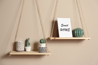 Photo of Wooden shelves with different decorative elements on beige wall