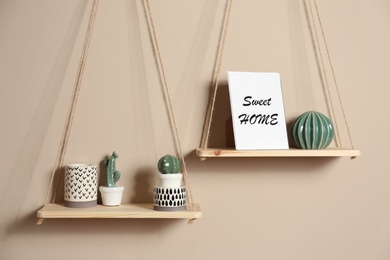 Wooden shelves with different decorative elements on beige wall