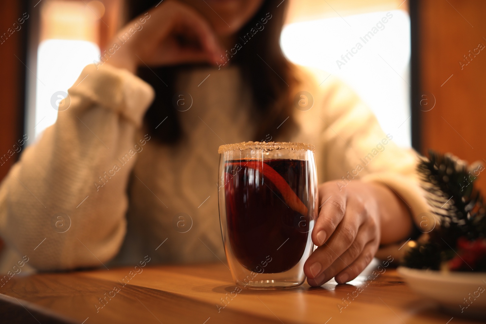 Photo of Woman with tasty mulled wine at table in cafe, closeup