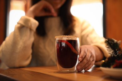 Photo of Woman with tasty mulled wine at table in cafe, closeup