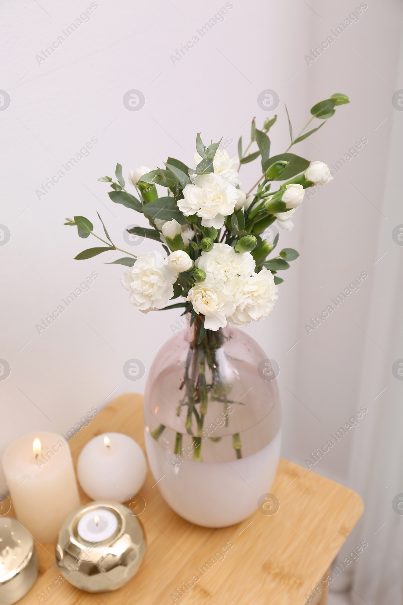 Photo of Beautiful flowers and burning candles on wooden dressing table indoors