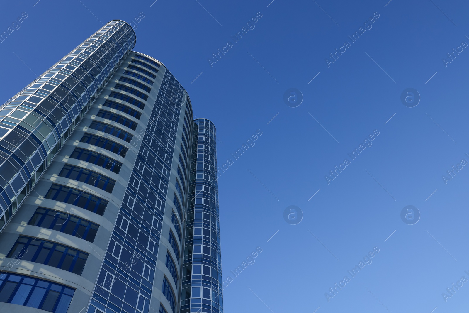 Photo of Beautiful skyscraper against blue sky on sunny day, low angle view
