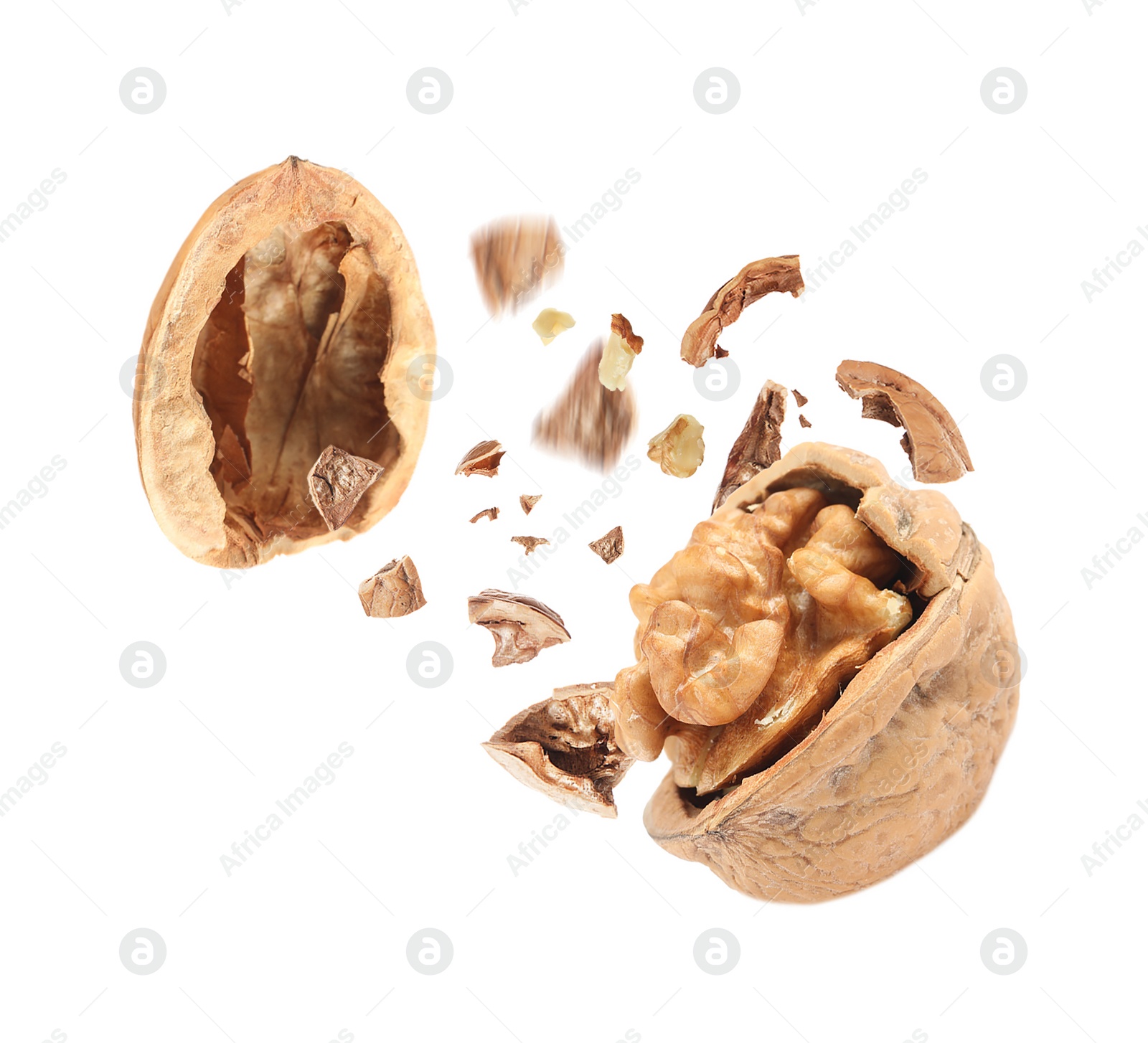 Image of Broken walnut and pieces of shell flying on white background