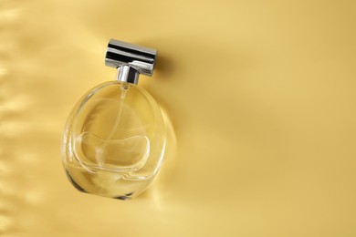 Photo of Perfume in bottle on golden background, top view. Space for text